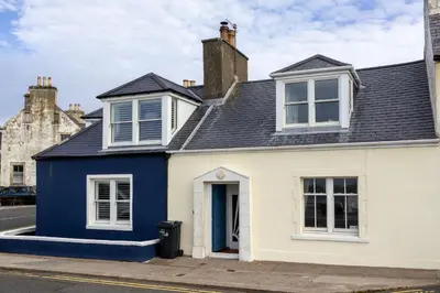a blue and white house on a street at Moir Cottage in Portpatrick