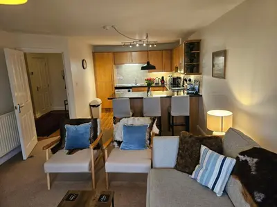 a living room with a couch and a kitchen at Carlisle Stunning 2 Bed Appt with Parking 5 mins J42 M6 in Carlisle