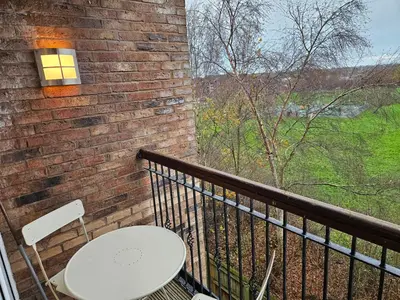 a white table and chairs on a balcony with a brick wall at Carlisle Stunning 2 Bed Appt with Parking 5 mins J42 M6 in Carlisle