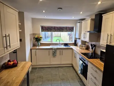 a kitchen with white cabinets and a sink and a window at Feather Bed Cottage - Dog Friendly Lakeland Retreat with Log Burner & Garden