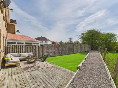 a backyard with a wooden deck with a couch and a lawn at The Haven Holiday Home in Woodend