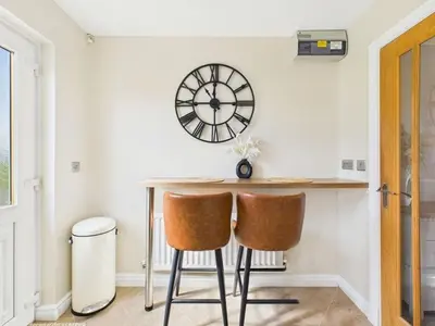a dining room with a table and a clock on the wall at The Haven Holiday Home in Woodend
