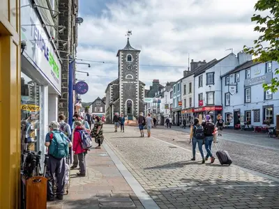 a group of people walking down a street with a church at 2 Bed in Cockermouth oc-sz431 in Bassenthwaite Lake