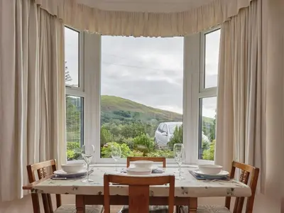 a dining room table with chairs and a large window at 2 Bed in Cockermouth oc-sz431 in Bassenthwaite Lake