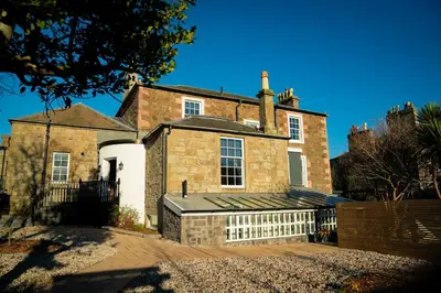 an old brick house with a fence in front of it at Bankhouse in Troon
