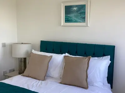 a bed with a green headboard and white pillows at Seascape - a Luxury Retreat on the Sea in Moffat
