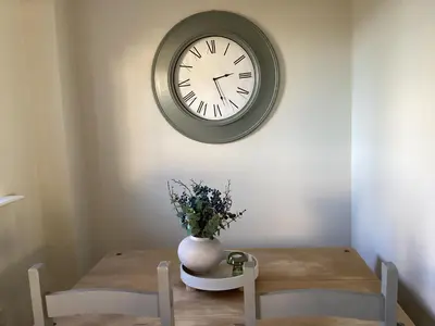 a dining room table with a clock on the wall at Seascape - a Luxury Retreat on the Sea in Moffat
