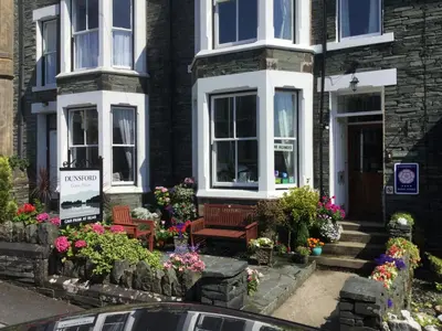 a house with benches and flowers in front of it at Dunsford Guest House in Keswick