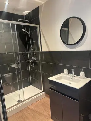 a bathroom with a shower and a sink and a mirror at The Briery in Workington