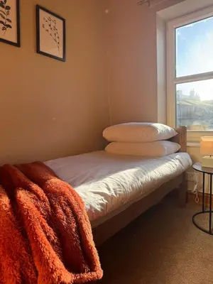 a bed with an orange blanket and a window at Central Carlisle Modern 4BD w Wi-Fi, Washer, & SmartTVs, close to M6 in Carlisle