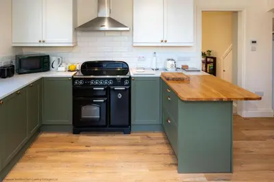 a kitchen with green cabinets and a black stove at Craignair in Castle Douglas