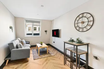a living room with a couch and a clock on the wall at Newly Renovated 1BR Steps from Hove Beach in Moffat