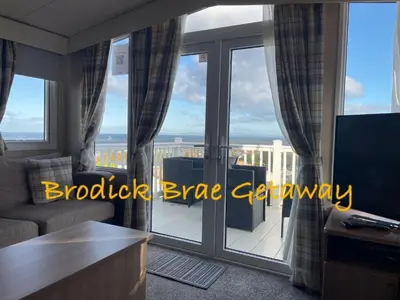 a living room with a couch and a large glass window at Brodick Brae Getaway in Dunure