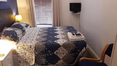 a bedroom with a bed with a blue and white quilt at Bed And Blueberry Two Bed Suite for 2,3, or 4 people in Douglas