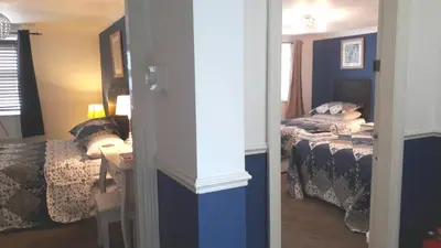 a bedroom with two beds and a table and a mirror at Bed And Blueberry Two Bed Suite for 2,3, or 4 people in Douglas