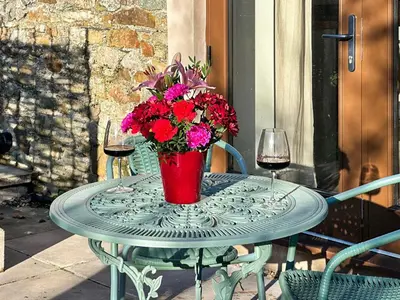 a table with a vase of flowers and a glass of wine at Lime Tree Barn in Tallentire