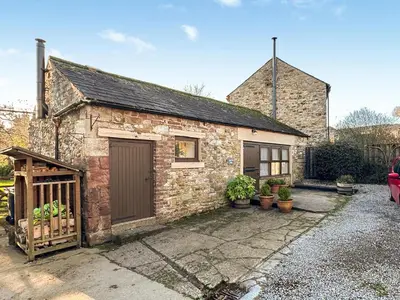 a stone house with a garage and a driveway at Lime Tree Barn in Tallentire