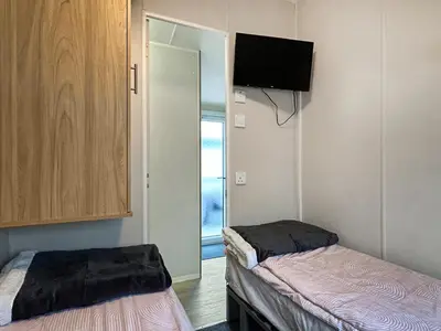 a room with two beds and a tv on the wall at Ali B's Craig Tara in Ayr