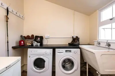 a laundry room with a washer and dryer and a sink at Orroland Holiday Cottages in Dundrennan