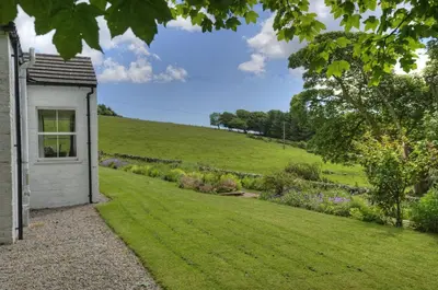 a house with a grassy yard next to a field at Orroland Holiday Cottages in Dundrennan