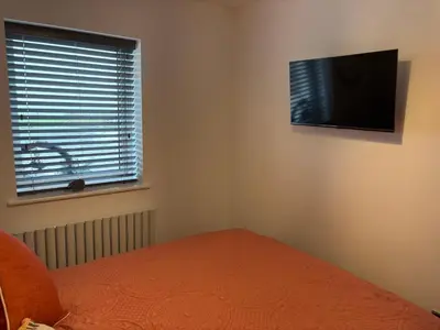 a bedroom with a bed and a television on the wall at Cross Beck Cottage in Allonby