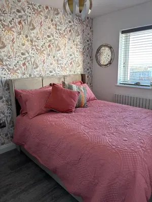 a bed with a pink comforter in a bedroom at Cross Beck Cottage in Allonby