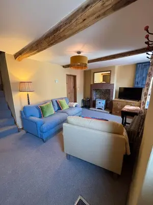 a living room with two blue couches and a couch at Maggies Cottage in Little Broughton