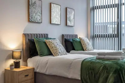 a bedroom with two beds with green pillows at Modern 2-Bed Flat with Balcony and Free Parking - Ideal for Contractors in Moffat