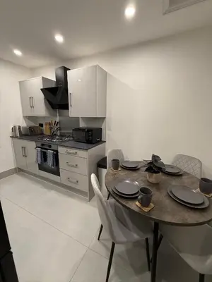 a kitchen with a table and chairs in a kitchen at Cosy Greenwich Flat Near -Cutty Sark, River & Park in Moffat