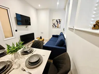 a living room with a table and a blue couch at Bright 2-Bed Apartment in Bury Town Centre in Moffat