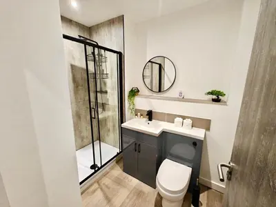 a bathroom with a shower and a toilet and a sink at Bright 2-Bed Apartment in Bury Town Centre in Moffat