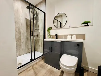a bathroom with a shower and a toilet and a sink at Bright 2-Bed Apartment in Bury Town Centre in Moffat