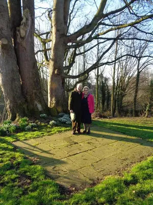 a man and woman walking down a sidewalk next to a tree at Garden flat at Broomfield in Moffat