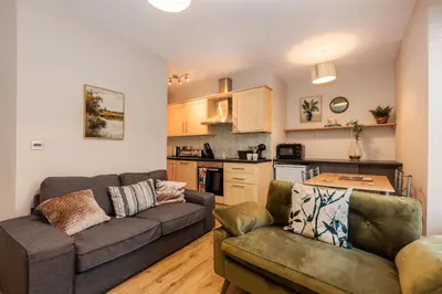 a living room with a couch and a kitchen at South Loft a Modern Apartment in Cockermouth in Cockermouth