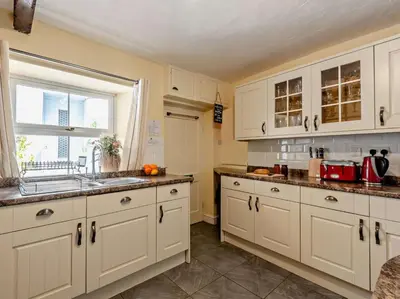 a kitchen with white cabinets and a sink and a window at 3 Bed in Maryport oc-sz102 in Allonby