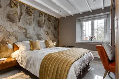 a bedroom with a large bed and a stone wall at Courtyard Cottage in Castle Douglas
