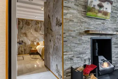 a living room with a stone wall with a fireplace at Courtyard Cottage in Castle Douglas