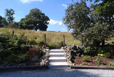 a garden with a set of stairs and rocks at Courtyard Cottage in Castle Douglas