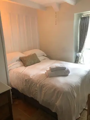 a bed with two pillows on it in a bedroom at Romantic Cottage, Port Isaac in Moffat