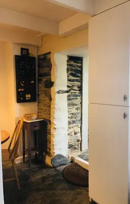 a room with a stone wall and a table and a refrigerator at Romantic Cottage, Port Isaac in Moffat