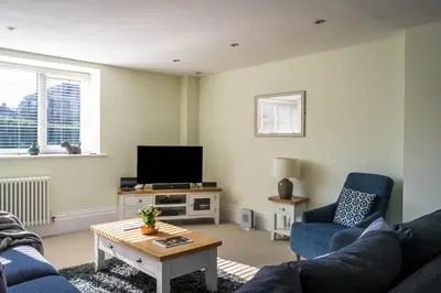 a living room with two blue couches and a tv at Old School Mews - Shanklin - Dog Friendly in Moffat