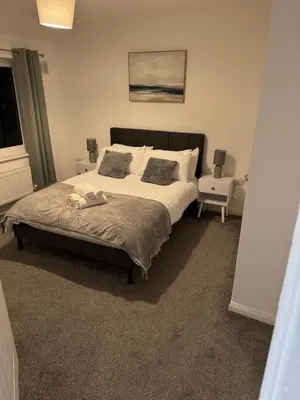 a bedroom with a large bed and a chair at Rowe Terrace Workington in Workington