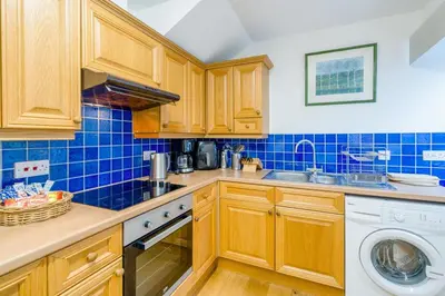a kitchen with wooden cabinets and a washer and dryer at 3 Bed in New Galloway oc-r34387 in New Galloway