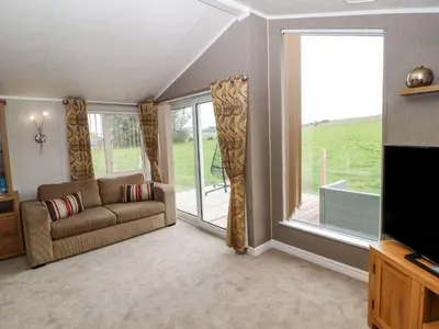 a living room with a couch and a large window at No 8 Hillcote Lodge in Cockermouth
