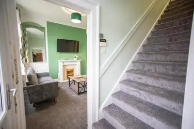 a hallway with a staircase with a chair and a television at The Woodrouffee retreat in Carlisle