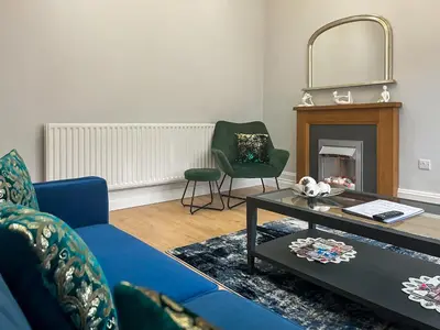 a living room with a blue couch and a fireplace at Lakes And Shores Retreat in Maryport