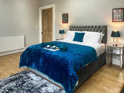 a bedroom with a large bed with a blue blanket at Lakes And Shores Retreat in Maryport