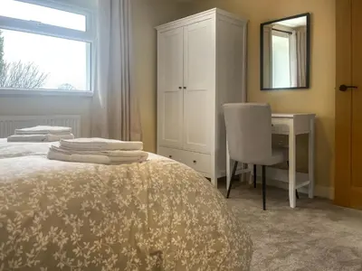 a bedroom with a bed and a desk and a mirror at Garth Cottage in Keswick