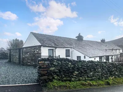 a white house with a stone wall in front of it at Garth Cottage in Keswick