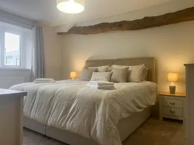 a bedroom with a bed with white sheets and a window at Garth Cottage in Keswick
